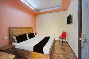 a bedroom with a bed and a red chair at Peralam Rooms in Peralam Junction