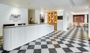 a woman standing at a counter in a lobby at Sercotel Pozuelo in Pozuelo de Alarcón