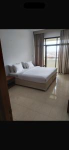 a large bed in a room with a large window at Nahda Tower Suite in Salalah
