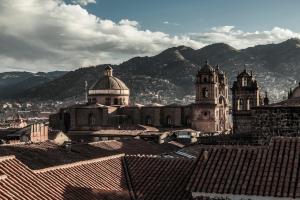 a group of buildings with mountains in the background at Hostal & Apartments El Triunfo in Cusco