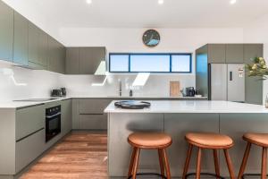 a kitchen with a large island with three stools at Fernleigh Stay in Fernleigh