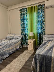 a bedroom with two beds and a lamp on a night stand at Golden Isles Paradise in Port-of-Spain