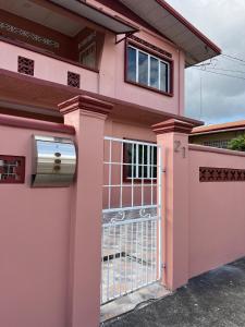 a pink house with a gate at Golden Isles Paradise in Port-of-Spain