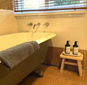 a bathroom with a tub and two bottles on a stool at Eucalyptus House in Pemberton +38 photos