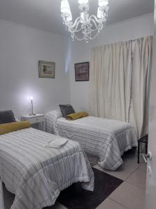 a bedroom with two beds and a chandelier at Temporario Martínez in General Pico