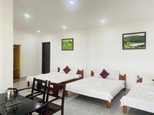 a room with three beds and a table and chairs at Boho NHH Apartment in Hanoi