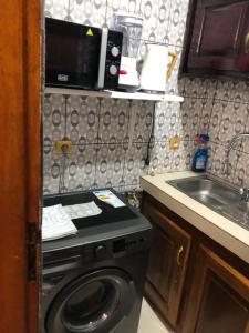 a small kitchen with a washing machine and a sink at AFRAAH GUEST House 2 in Yaoundé