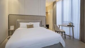 a bedroom with a large white bed and a table at Alcola Boutique Villa - Dania Unit in Tlekung