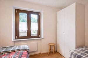 a bedroom with a window and a bed and a stool at Suite Bormio - with WIFI & Netflix in Piatta