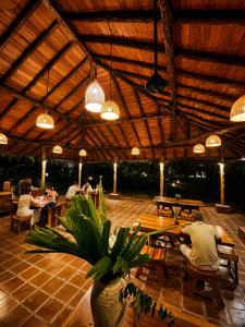 a group of people sitting at tables in a patio at The Coconut Experience Eco Lodge Wilpattu in Nagamadu