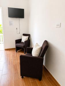 a living room with two chairs and a flat screen tv at Bon Appetit Hotel & Restaurant Barahona in Santa Cruz de Barahona