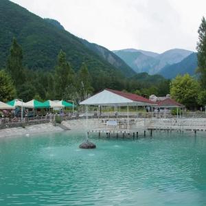 a body of water with a dock and buildings and mountains at Narınqala Hotel in Sheki