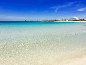 a beach with clear blue water and buildings in the background at Hotel Blu in Porto Cesareo