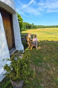 two women sitting on a bench in a field at Partsi Veski in Partsi