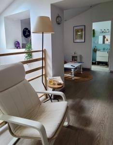 a living room with a white chair and a table at Métairie du Peyré in Pauilhac