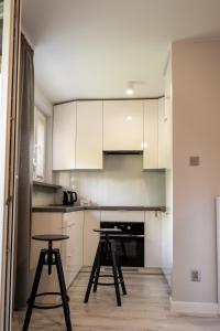 a kitchen with white cabinets and two stools in it at Apartament Targowa 9A41 in Uniejow