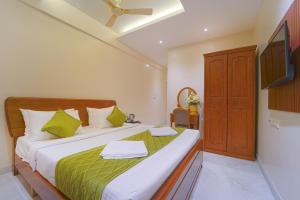 a bedroom with a bed with green sheets and a flat screen tv at YAFA Palace in Rāmanāthapuram