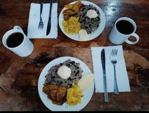 a table with two plates of food and two cups of coffee at Cabinas Toucan in Chachagua