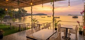 a restaurant with tables and chairs with a view of the water at GS Home on the Bay - Sea & forest view glass studio in Vagator