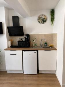 a kitchen with white cabinets and a sink at Escale Tropicale in Lectoure