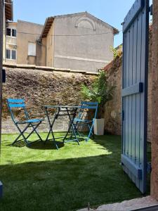 two blue chairs and a table in a yard at Escale Tropicale in Lectoure