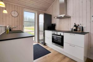 a kitchen with white cabinets and a refrigerator and a sink at 16666-Farevejle-Karuphoj-4-E in Fårevejle