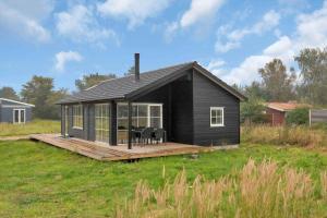 a black house with a deck in a field at 16666-Farevejle-Karuphoj-4-E in Fårevejle