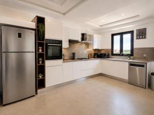 a kitchen with white cabinets and a stainless steel refrigerator at Villa ines in Taguermess