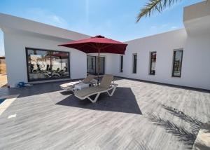 a patio with two lounge chairs and an umbrella at Villa ines in Taguermess