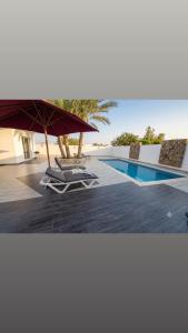 a pool with a table and an umbrella and chairs at Villa ines in Taguermess