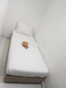 a white bed with a brown item on it at Swing & Pillows - Kuala Selangor in Kuala Selangor