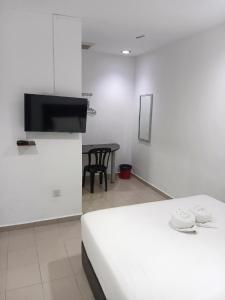 a white room with a bed and a table at Swing & Pillows - Kuala Selangor in Kuala Selangor