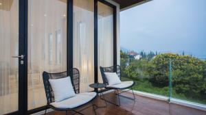 two chairs and a table on a balcony with windows at Alcola Boutique Villa - Astonia Unit in Batu