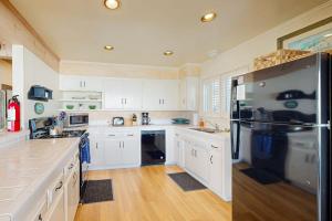 a kitchen with white cabinets and a black refrigerator at Oceanfront Delight in Cayucos