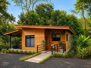 a small cabin with a porch in a forest at Arenal Rain Forest Lodge in Fortuna