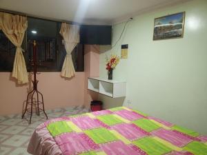 a bedroom with a bed with a pink and green quilt at Hotel Casa Nova in Tulcán