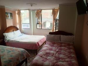 a small room with two beds and a window at Hotel Casa Nova in Tulcán