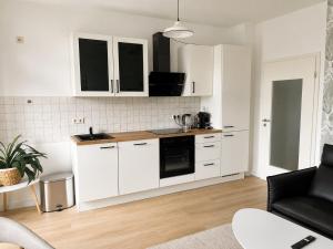 a kitchen with white cabinets and a black appliance at Modernes Design-Apartment mit Balkon & WLAN in Bautzen