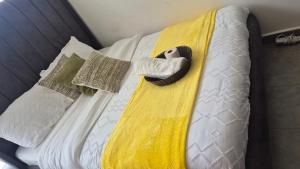 a bed with a yellow and white blanket and pillows at Hise Haven Stays in Kiambu