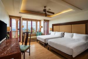 a hotel room with two beds and a balcony at Centara Grand Beach Resort Phuket in Karon Beach