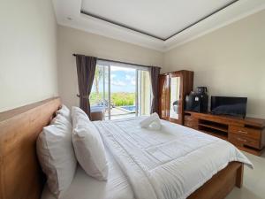 a bedroom with a bed with a television and a window at Bunut Sari Guesthouse in Ungasan