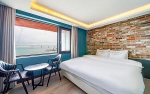 a bedroom with a large bed and a brick wall at Busan Gwangalli SEAYOU HOTEL in Busan
