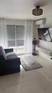 a living room with a couch and some windows at Studio cosy Ducos in Ducos