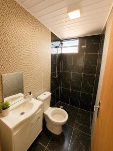 a bathroom with a white toilet and a sink at Cabaña Acuña in Chuy