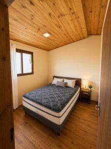 a bedroom with a bed in a room with wooden ceilings at Cabaña Acuña in Chuy