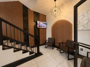 a lobby with a staircase and two chairs and a tv at Sereno Business Inn in Ensenada +5 photos