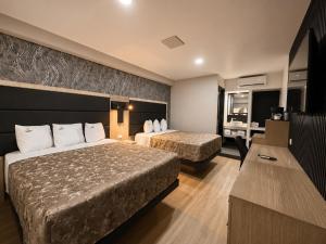 a hotel room with two beds and a desk at Sereno Business Inn in Ensenada