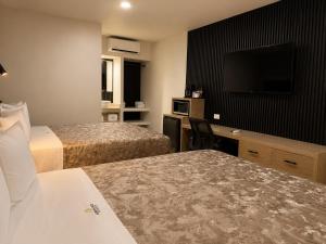 a hotel room with two beds and a flat screen tv at Sereno Business Inn in Ensenada