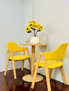 two yellow chairs and a table with a vase of flowers at Magic Garden Residence Bangkok in Bangkok +22 photos