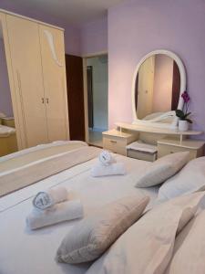 a large white bed with two towels on it with a mirror at Nano Apartmani in Smokvica